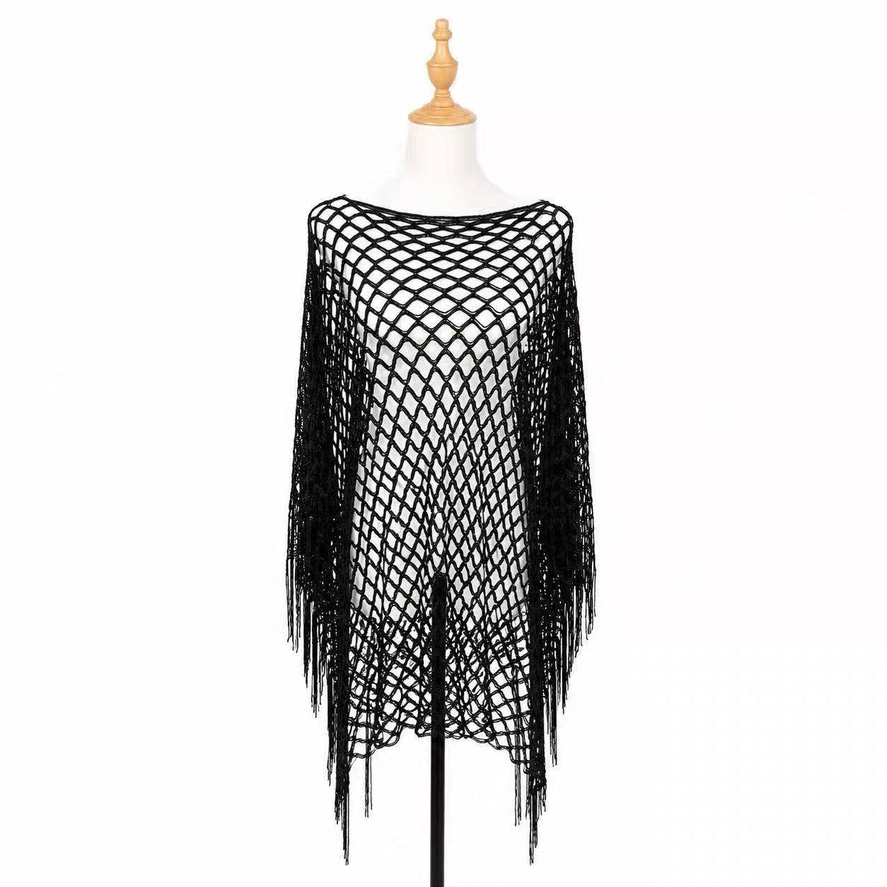 A black open-knit fringed poncho top displayed on a white dress form mannequin against a plain white background.
