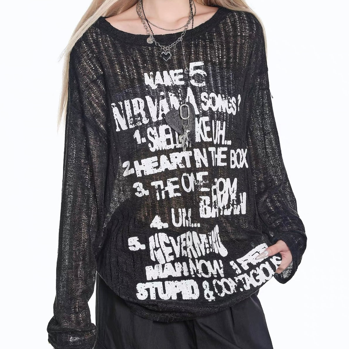 Person wearing a black outfit with sheer sleeves and ruffled skirt against a white background