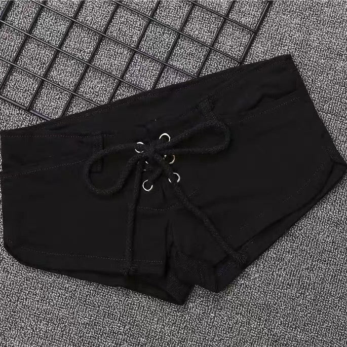 Black shorts with drawstring on a textured gray surface