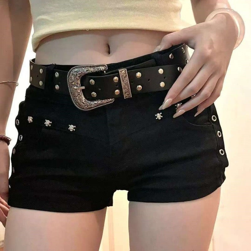 Person wearing black shorts with decorative buttons and a studded belt.
