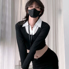 Femboy wearing a black outfit with a white collar and black mask against a neutral background