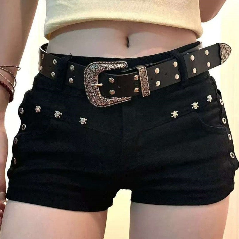 Black shorts with a studded belt on a neutral background