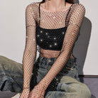 Person wearing a sheer mesh top and cargo pants against a plain background