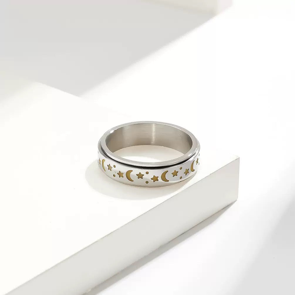 Silver ring with gold star and moon designs on a white background
