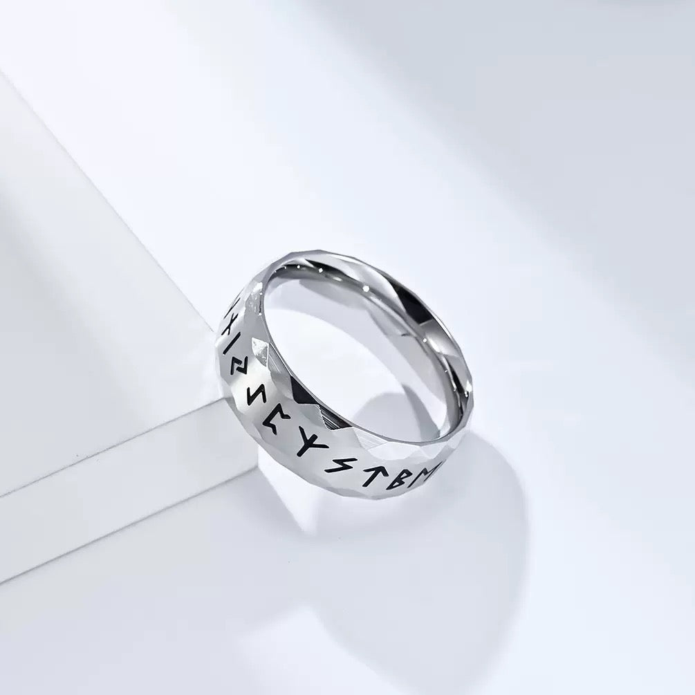Silver ring with engraved text on a light gray background