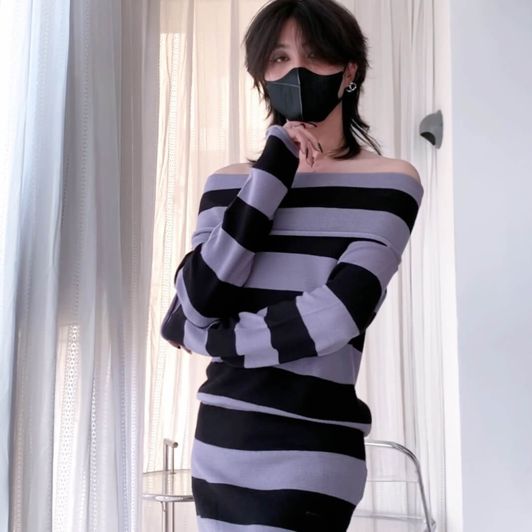 Person wearing a black and gray striped dress with a white background