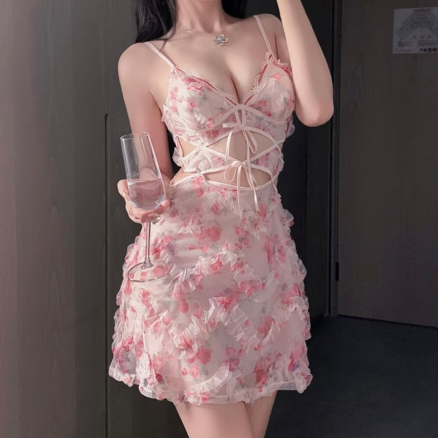 Femboy wearing a sweet lace camisole nightgown holding a glass in a dimly lit room.