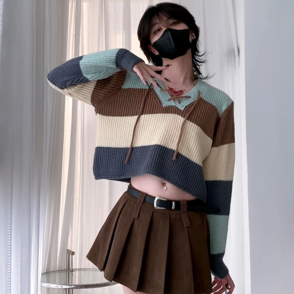 A femboy wearing a v neck lace up color block sweater