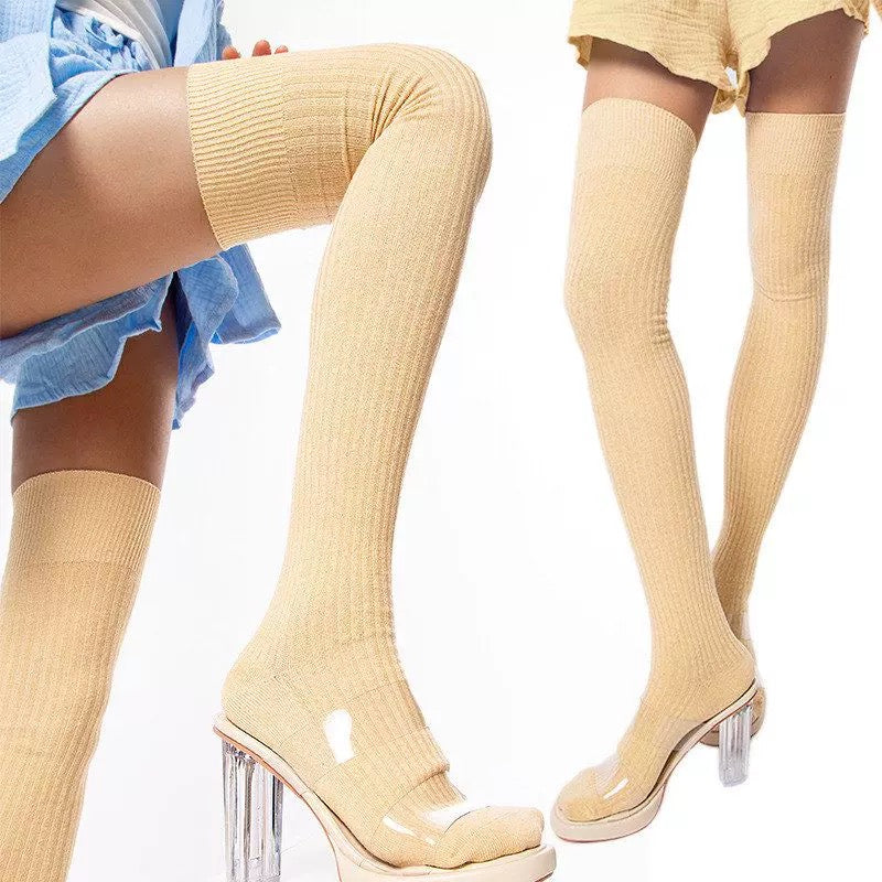 Yellow thigh-high socks with clear high heels worn by a person on a white background